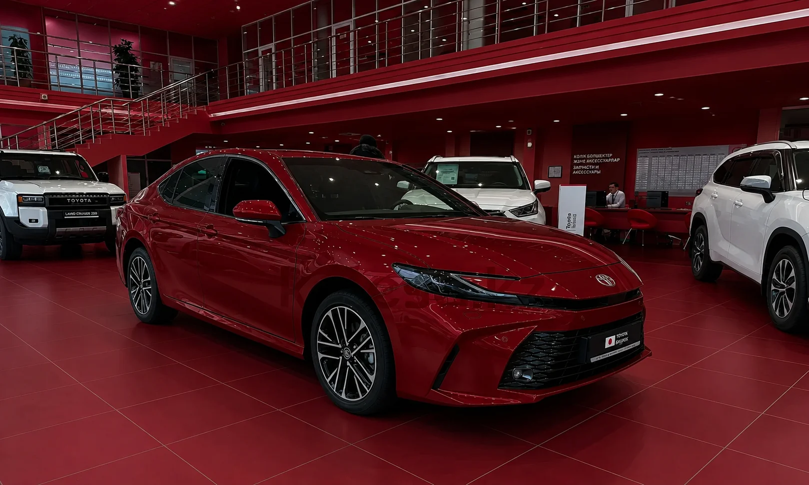 | Toyota Camry Trims 2026: Which One Is Best? Red 2026 Toyota Camry displayed inside a showroom featuring rich red ambient lighting