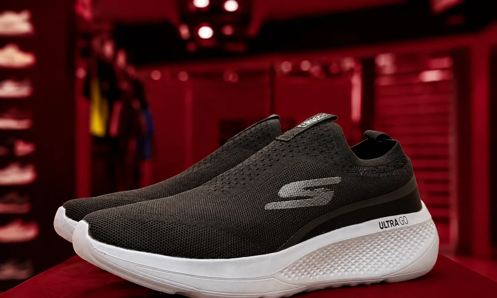 Black Skechers slip-on sneaker on a glowing red display