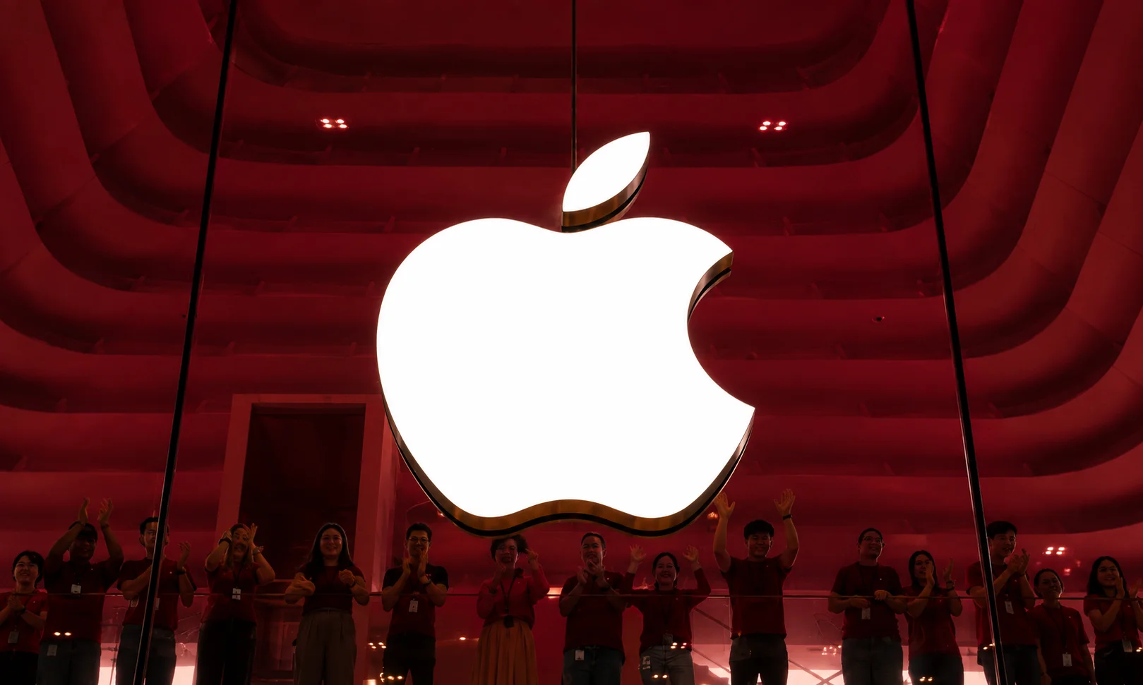 The classic Apple logo illuminated on a device within a red-themed room.