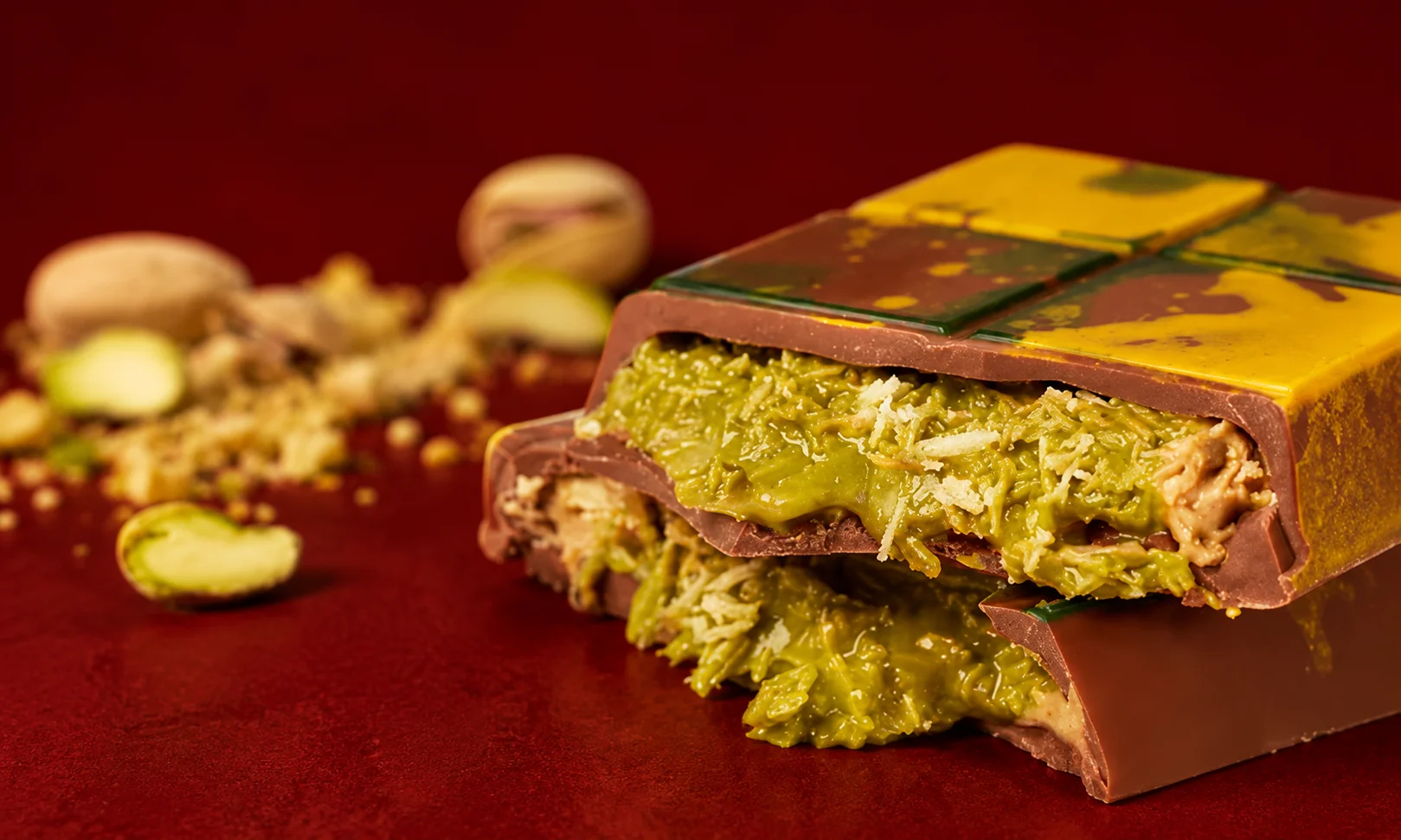 Gourmet Dubai chocolate bars featuring rich pistachio filling on a dark red surface