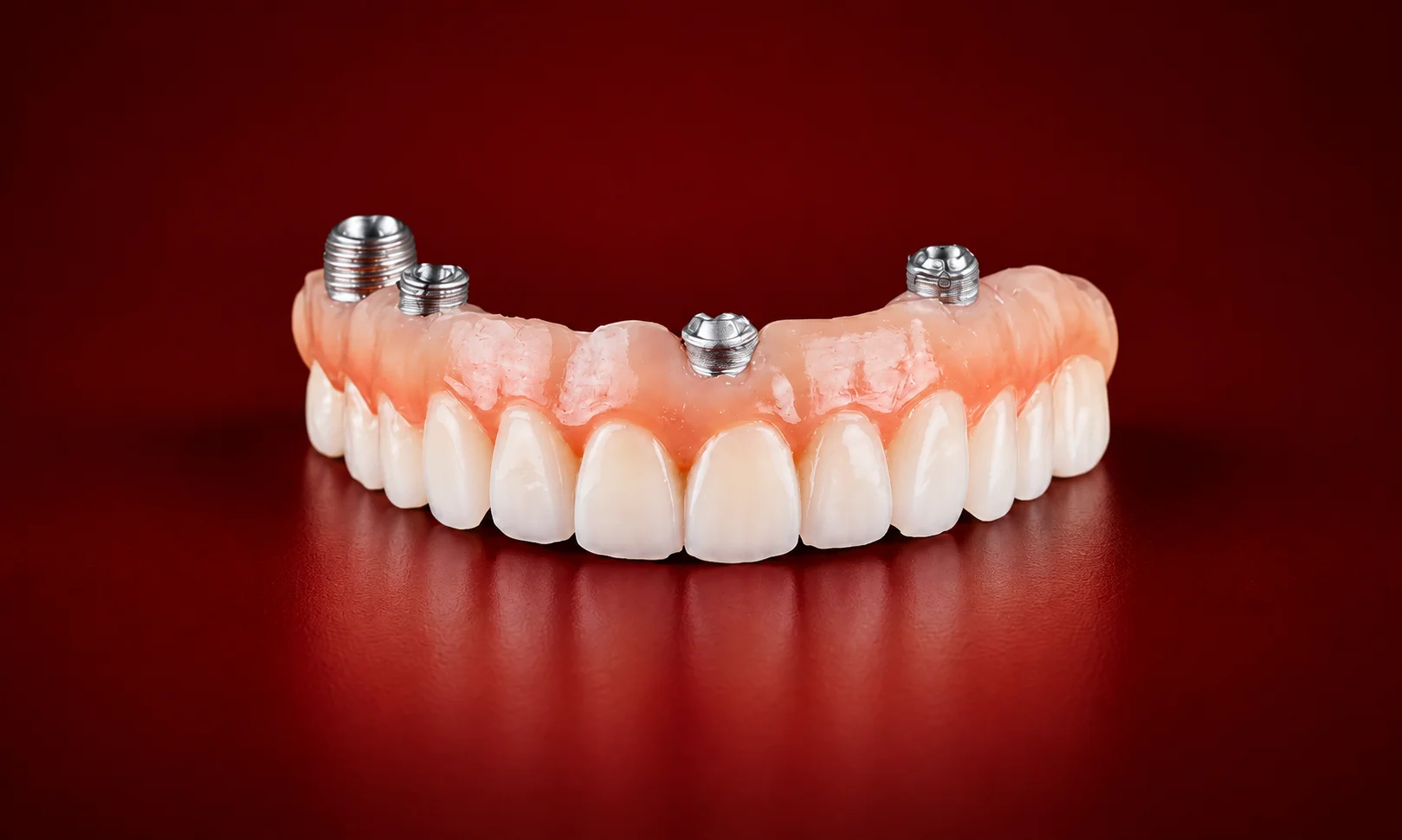 Front view of All-on-4 dental implants resting on a sleek red surface