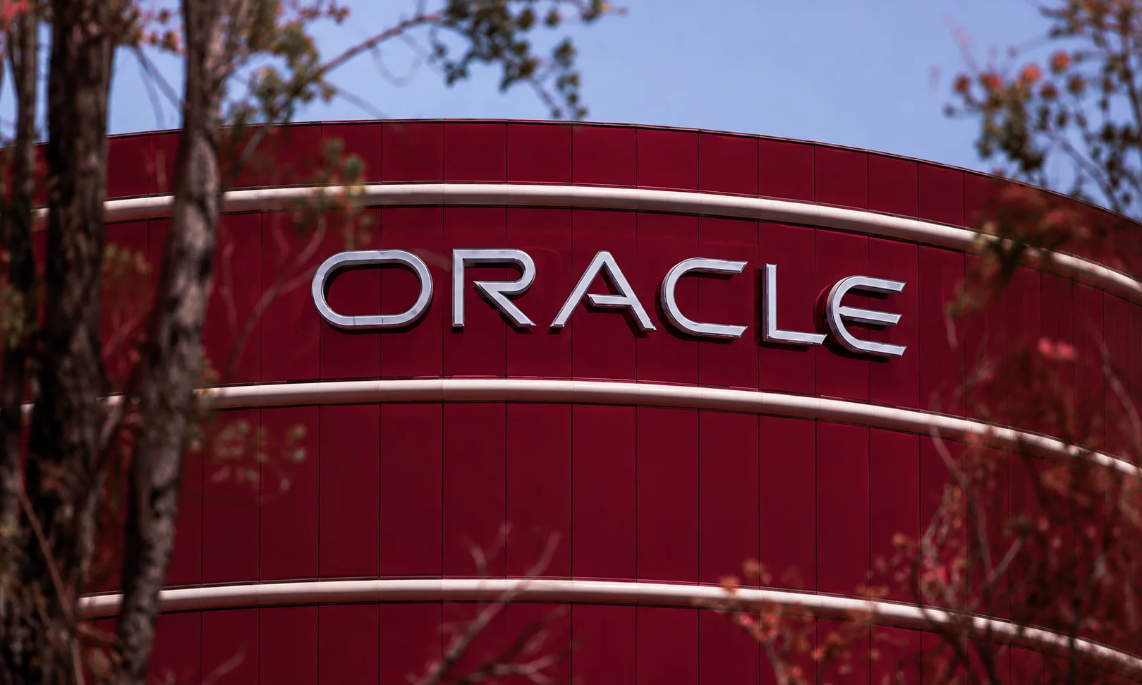 The Oracle corporate logo and exterior architecture viewed in a dark ambient lighting.